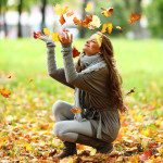 woman drop leaves in autumn park